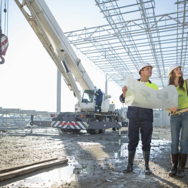 Site manager and architect checking blueprint on construction site